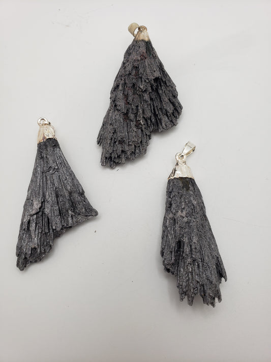 A trio of Black Kyanite Pendants featuring silver bails on a white backdrop, showcasing their fan-like, layered texture.