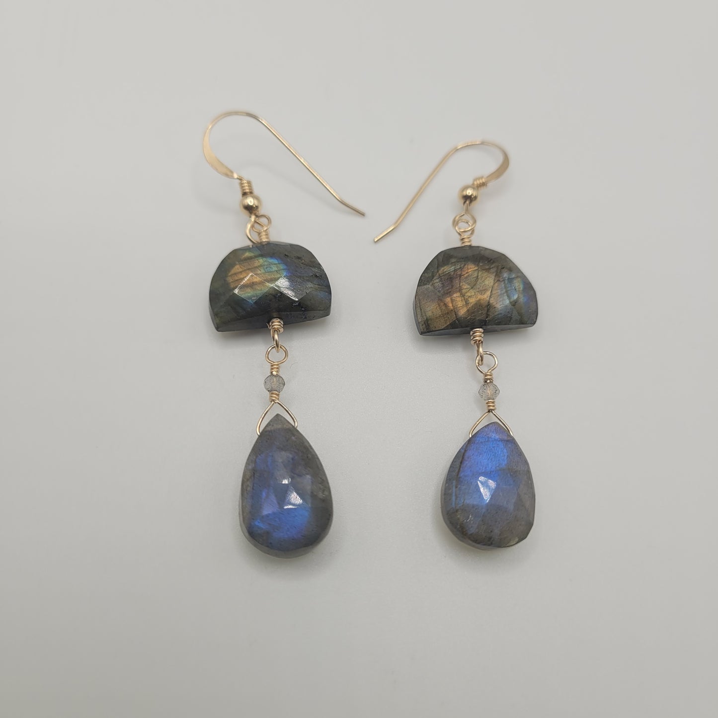A pair of gold filled labradorite drop earrings with a half moon shape above a teardrop pendant