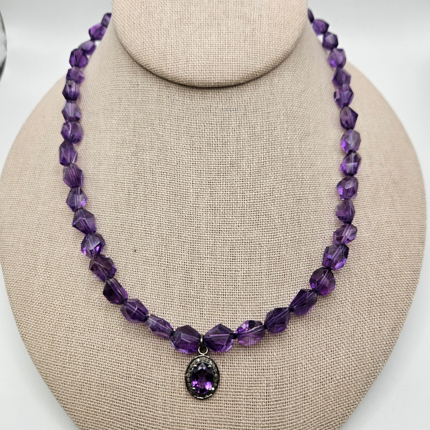 A purple amethyst crystal necklace with a diamond-shaped pendant