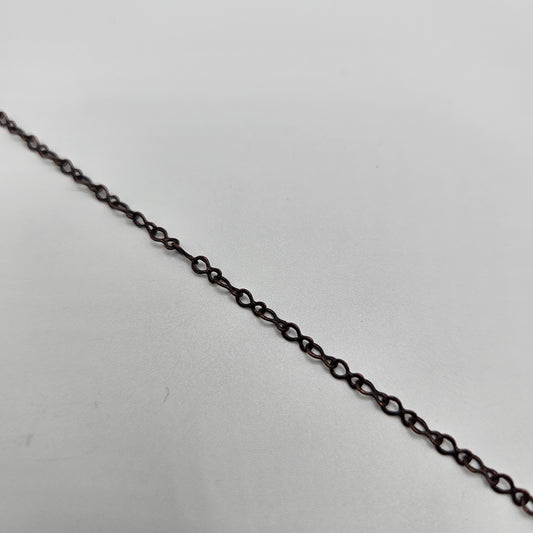 A close-up image of an antique copper fine teardrop chain against a white background.