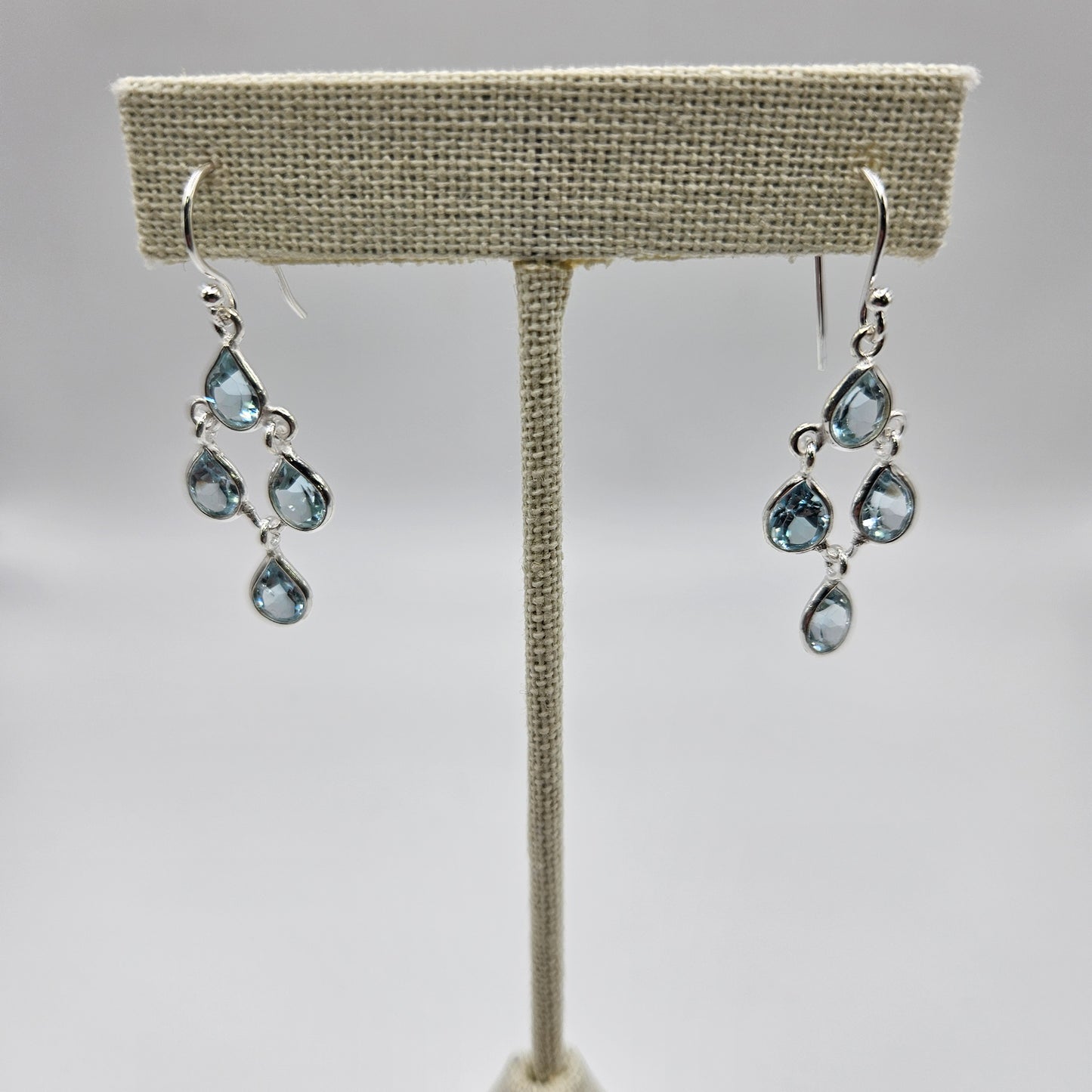 A pair of sterling silver teardrop faceted earrings with blue topaz stones.