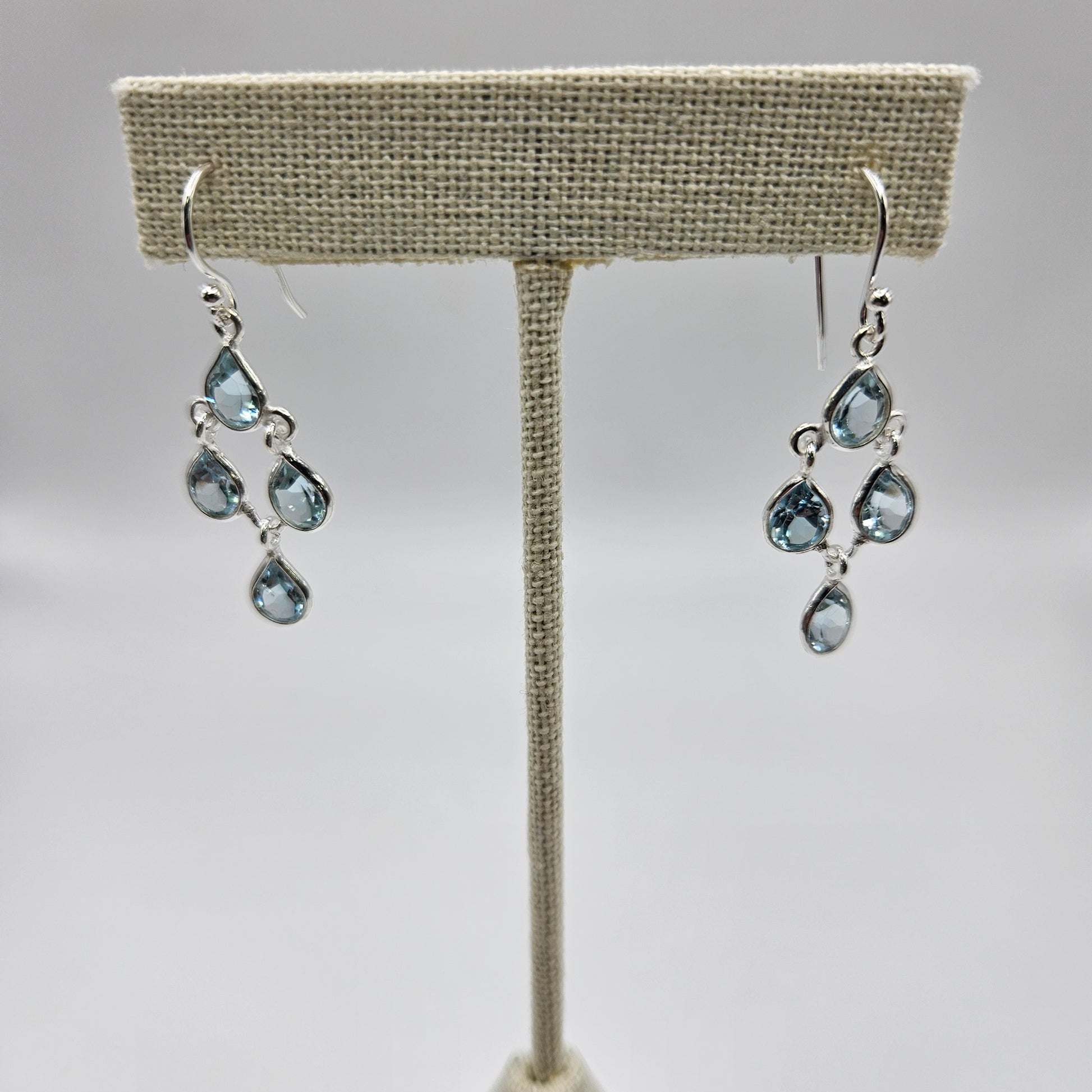A pair of sterling silver teardrop faceted earrings with blue topaz stones.