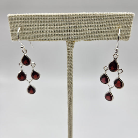 A pair of sterling silver teardrop faceted earrings with red gemstones.