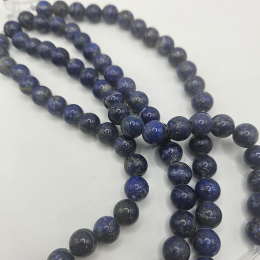 Product Data:
  Product Name: 10mm Lapis Lazuli Large Hole Bead Strand
Rewritten Sentence:
A "10mm Lapis Lazuli Large Hole Bead Strand" featuring round blue stones is arranged in multiple strands on a white surface. The beads exhibit a smooth, polished finish with subtle variations in color and texture.