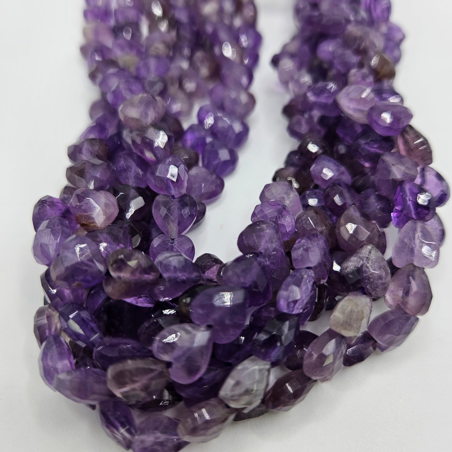 Close-up view of the 8mm Amethyst Faceted Heart Bead Strand, showcasing each bead's vibrant purple hues. The closely packed, faceted heart shapes create a rich and textured appearance.