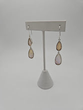 The Sterling Silver Butterfly Medium Tear Double Earrings in neutral tones are gracefully displayed on a white stand against a simple backdrop. Their delicate, minimalist design embodies the elegance of butterfly jewelry, capturing both simplicity and artistry in every detail.