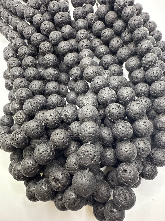 Close-up of dark gray volcanic beads on a white background.10mm Lava Rock Round.