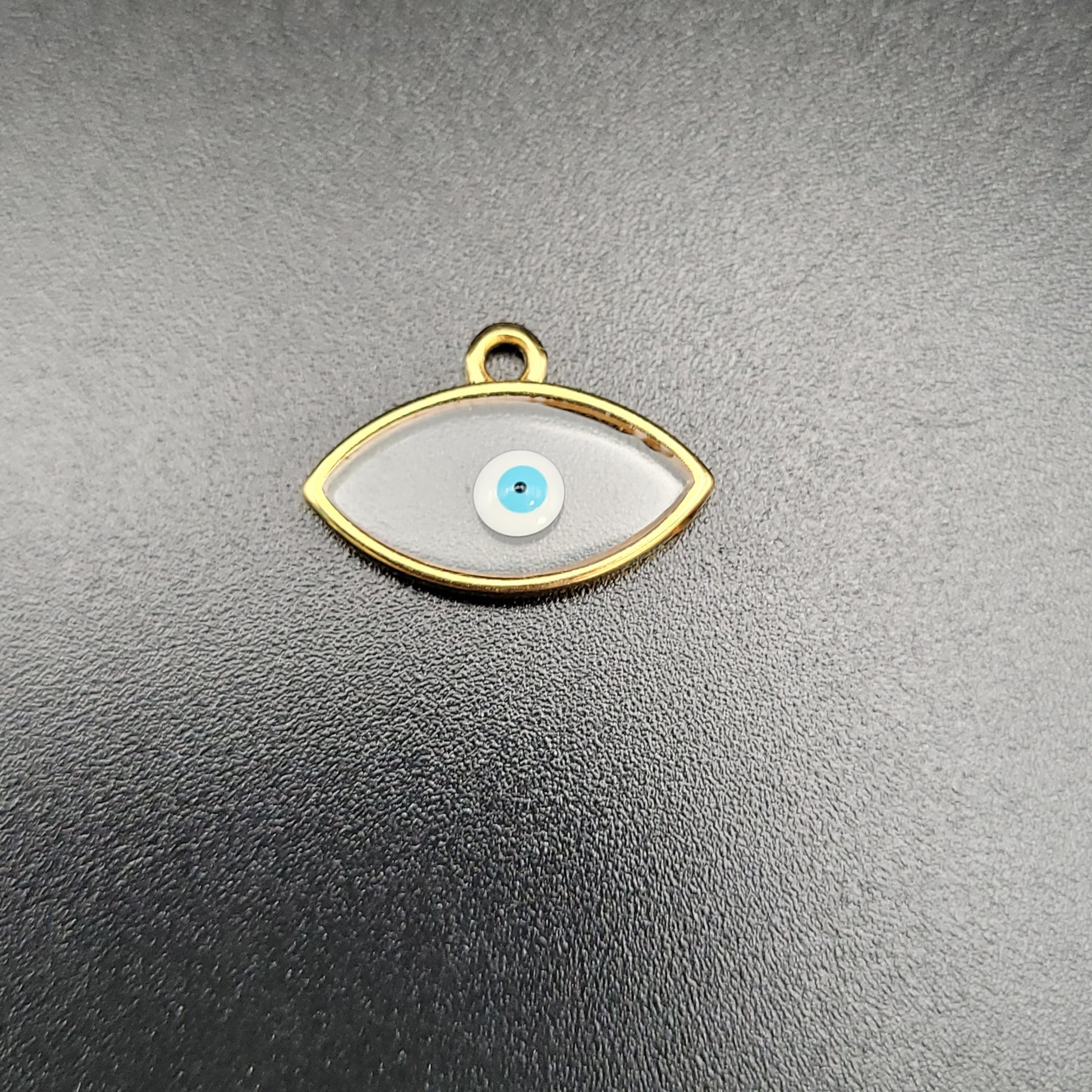 A gold-plated charm in the shape of an eye with a clear and blue enamel design