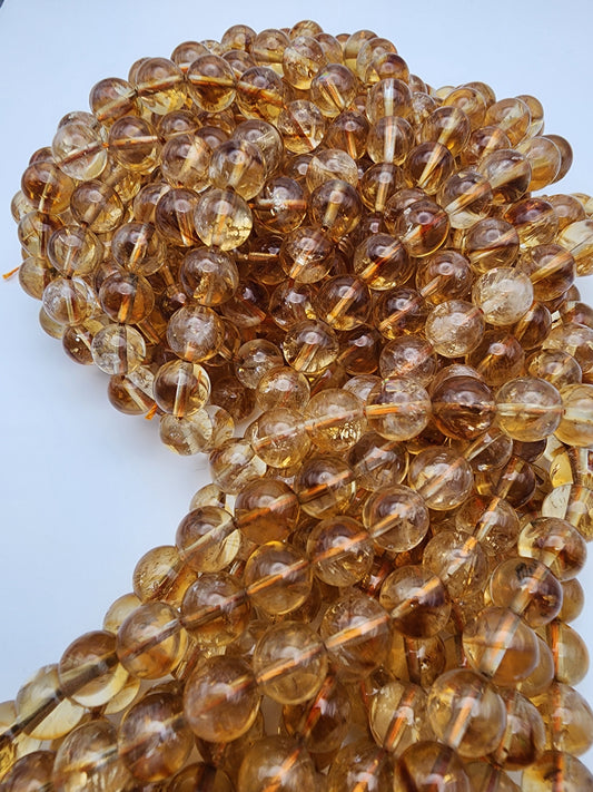 Close-up view of a string of 8mm Citrine Round beads with a glossy finish, elegantly coiled against a light background.
