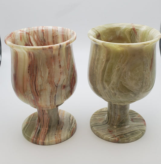 Two Onyx Goblets with a glossy finish, displaying swirling red and green patterns, stand side by side on a plain background. These items feature textured surfaces and unique colors that highlight intricate natural designs—perfect for captivating online sales in any product description.