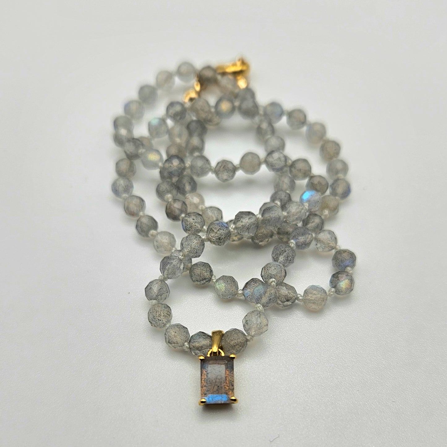 A knotted necklace featuring a mix of beige and blue labradorite beads