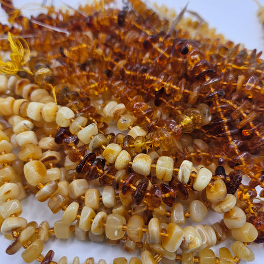 Close-up of the Large Yellow Amber Chips Bead Strand, featuring polished beads in a spectrum of honey, gold, and light yellow hues. The sizable beads are irregularly shaped and strung tightly together, showcasing a shiny and translucent finish.