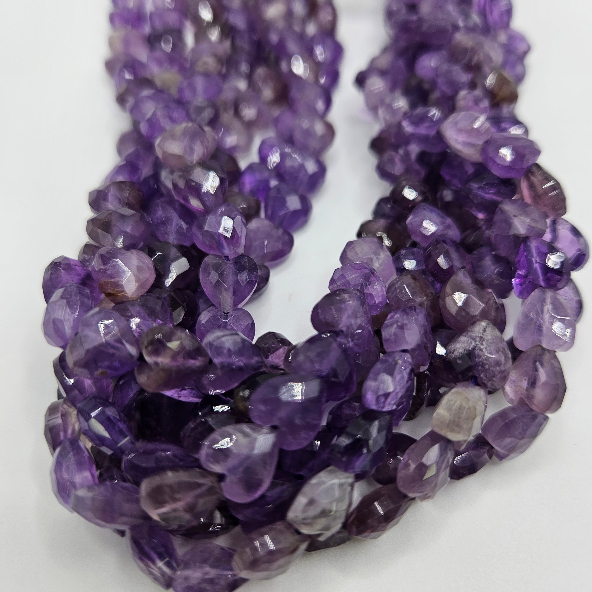 Close-up view of the 8mm Amethyst Faceted Heart Bead Strand, showcasing each bead's vibrant purple hues. The closely packed, faceted heart shapes create a rich and textured appearance.