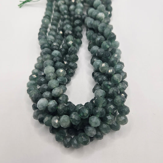 Close-up of multiple strands of the 8mm Green Jade Faceted Rondelle Bead Strand, showcasing their dark green color arranged in a loop on a white background. These beads feature a reflective surface that enhances their texture and vibrancy.