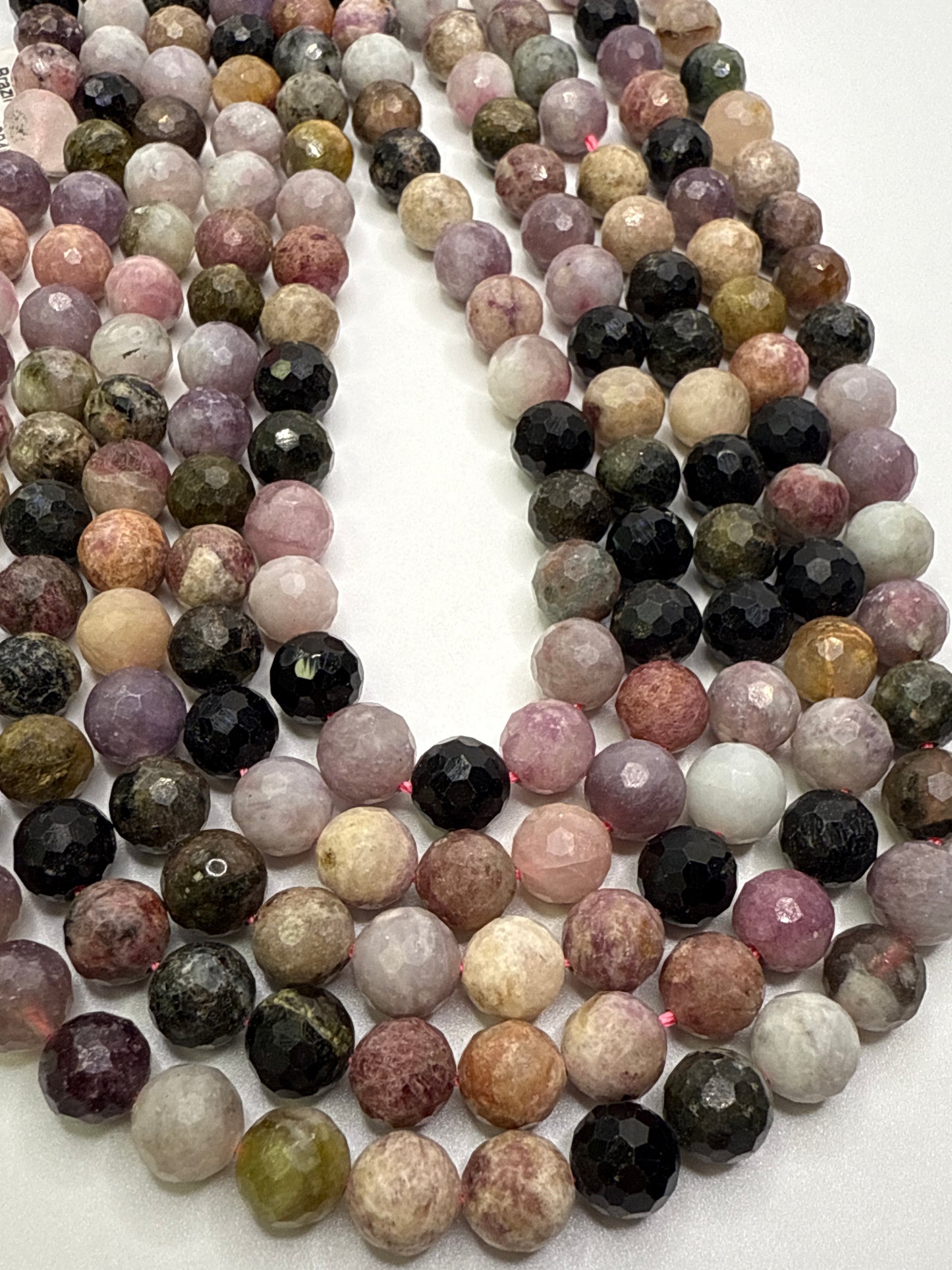 8mm Watermelon Tourmaline Faceted Round. Multicolored gemstone beads arranged in a circular pattern on a white background.