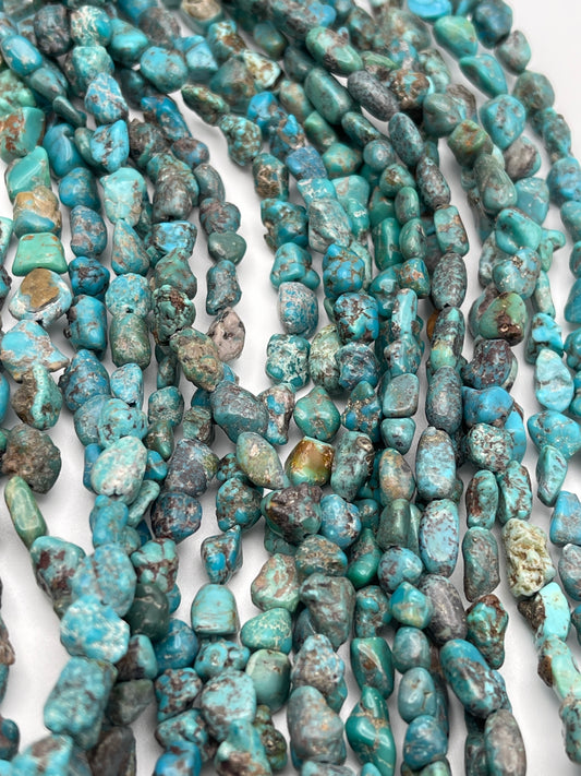 Close-up view of multiple strands of 6-8mm Turquoise Chunk beads, showcasing a variety of blue-green hues with natural veining and textures, set against a plain white background.