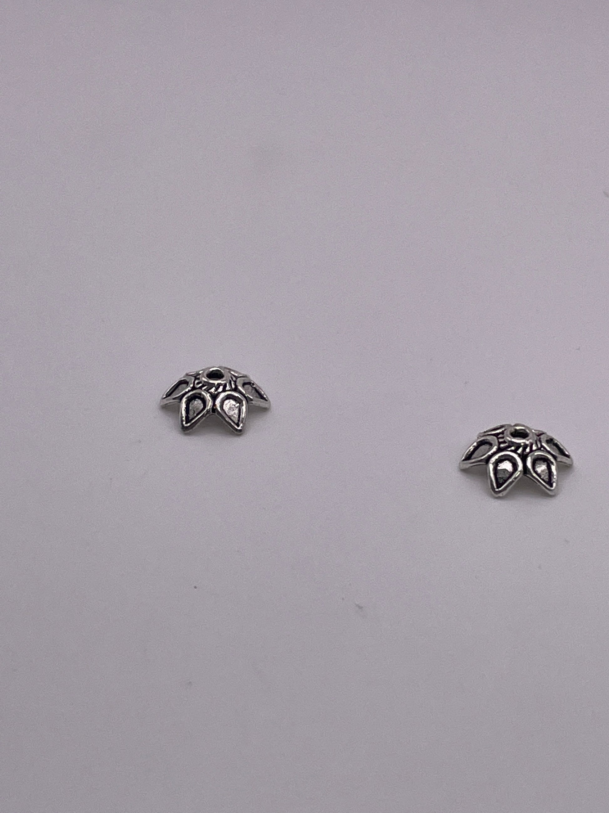Two Pewter Bead Cap .45 studs with intricate flower-shaped detailing, placed on a plain light gray background.
