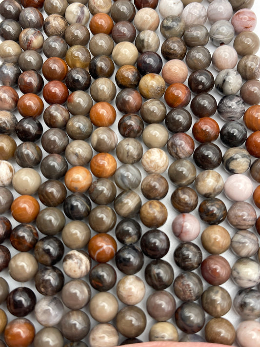 The 8mm Round Petrified Wood collection features polished, spherical beads in an array of earthy tones, including brown, grey, beige, and hints of reddish-orange. These beads are meticulously arranged in neat parallel rows to highlight their smooth, glossy surfaces and natural stone patterns.